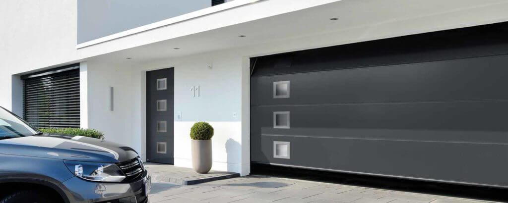 Een grijze Hörmann garagedeur en voordeur als versiering voor de contact en openingstijden pagina van Hensen Solid Systems